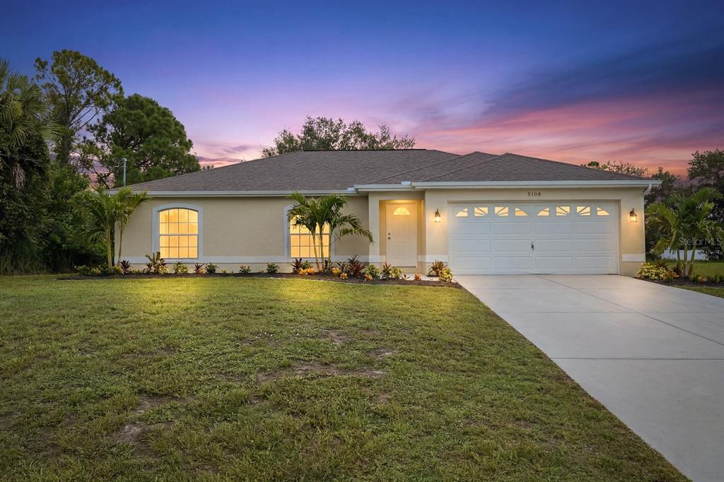 A single-story house with a beige stucco exterior, a two-car garage, and a concrete driveway — 5108 WEATHERTON STREET, NORTH PORT, FL