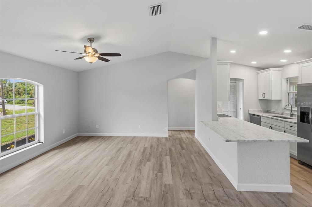 An open-concept living area with wood-look flooring, a ceiling fan, and an adjacent kitchen — 5108 WEATHERTON STREET, NORTH PORT, FL