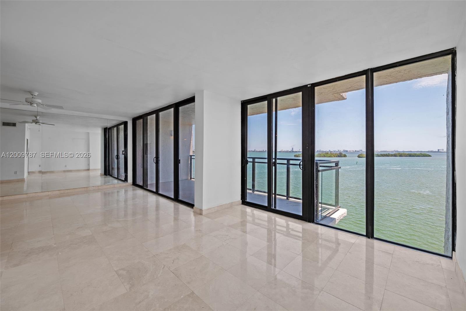 A bright, tiled living area features floor-to-ceiling windows with expansive water views — 7751 NE Bayshore Ct # 7B, Miami FL 33138, MIAMI, FL