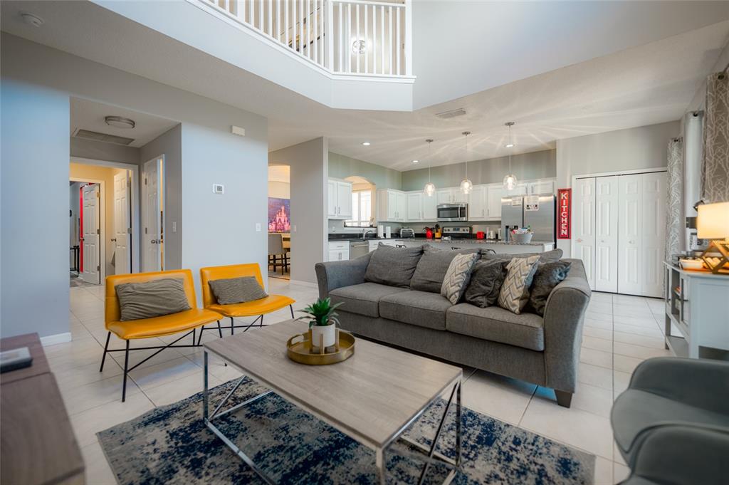 A living room with a grey sofa, two yellow chairs, and an open-concept kitchen — 8663 LA ISLA DRIVE, KISSIMMEE, FL