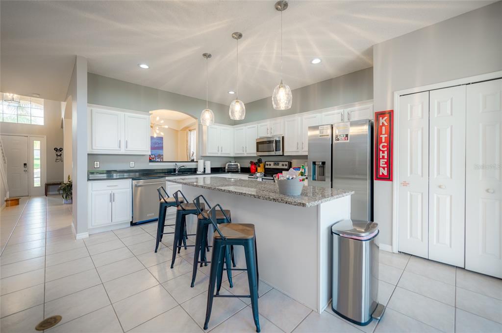 A kitchen features white cabinets, granite countertops, stainless steel appliances, and a breakfast bar — 8663 LA ISLA DRIVE, KISSIMMEE, FL