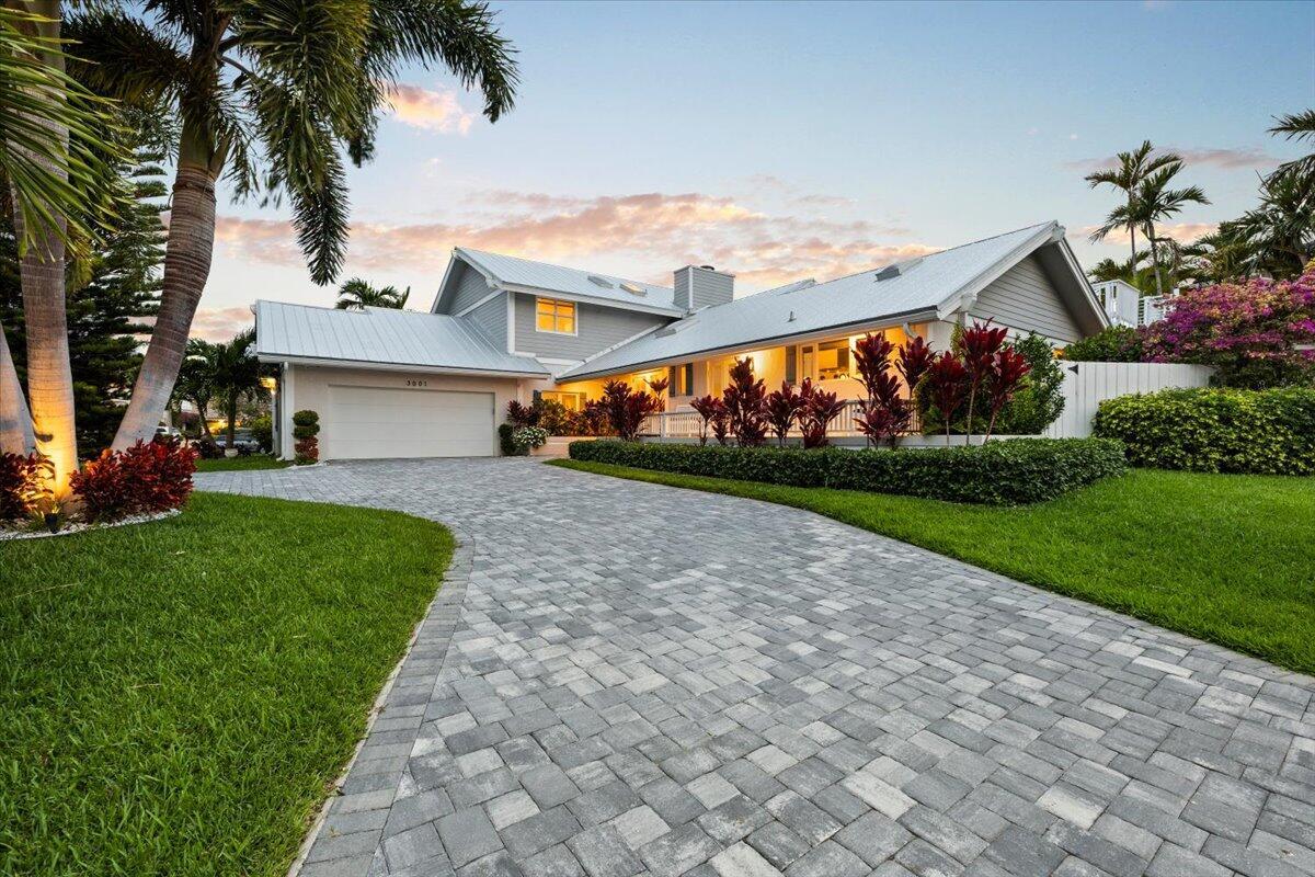 A gray house with a metal roof and a paved driveway sits behind a lawn — 3001 Jasmine Court, Delray Beach FL 33483, DELRAY BEACH, FL