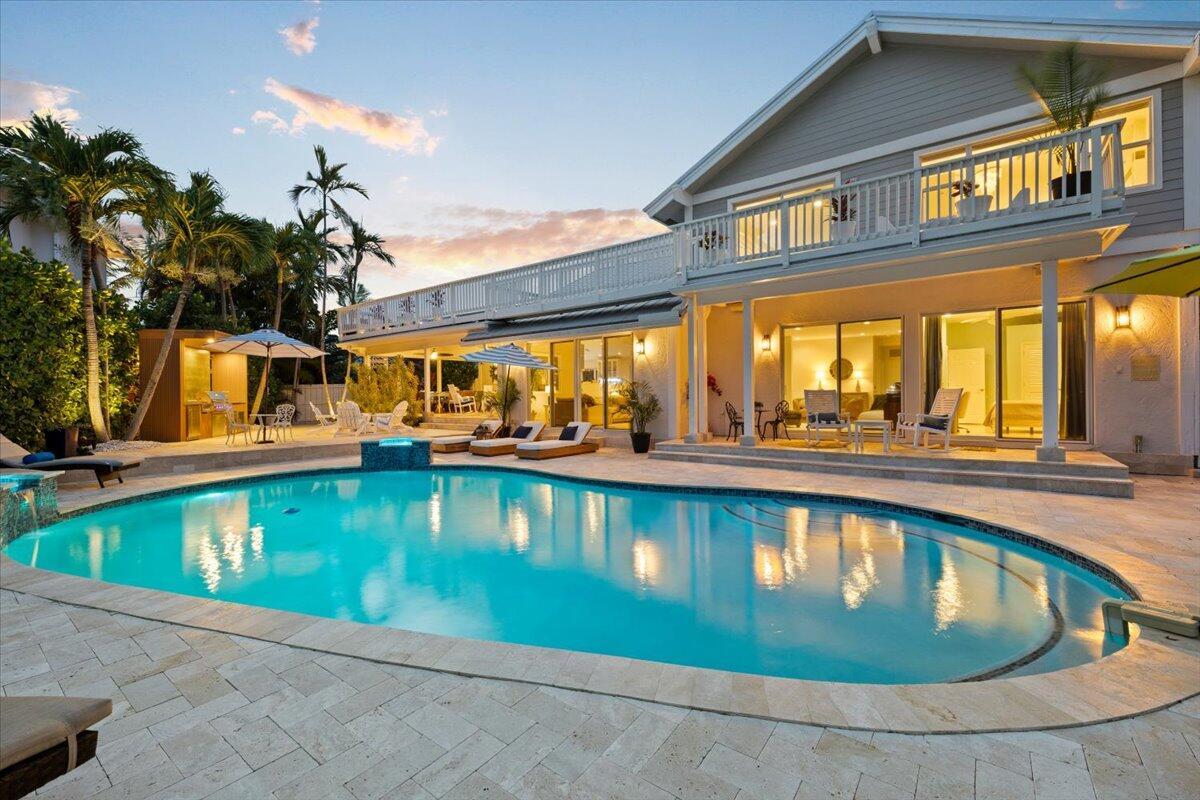 A two-story house with a balcony overlooks a swimming pool on a stone patio — 3001 Jasmine Court, Delray Beach FL 33483, DELRAY BEACH, FL