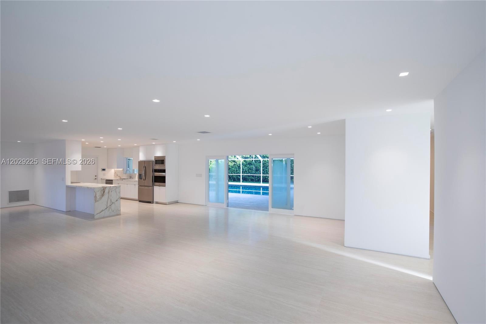A minimalist open-concept living area features white walls, light flooring, and a marble-topped kitchen island — 145 S Prospect Dr, Coral Gables FL 33133, CORAL GABLES, FL