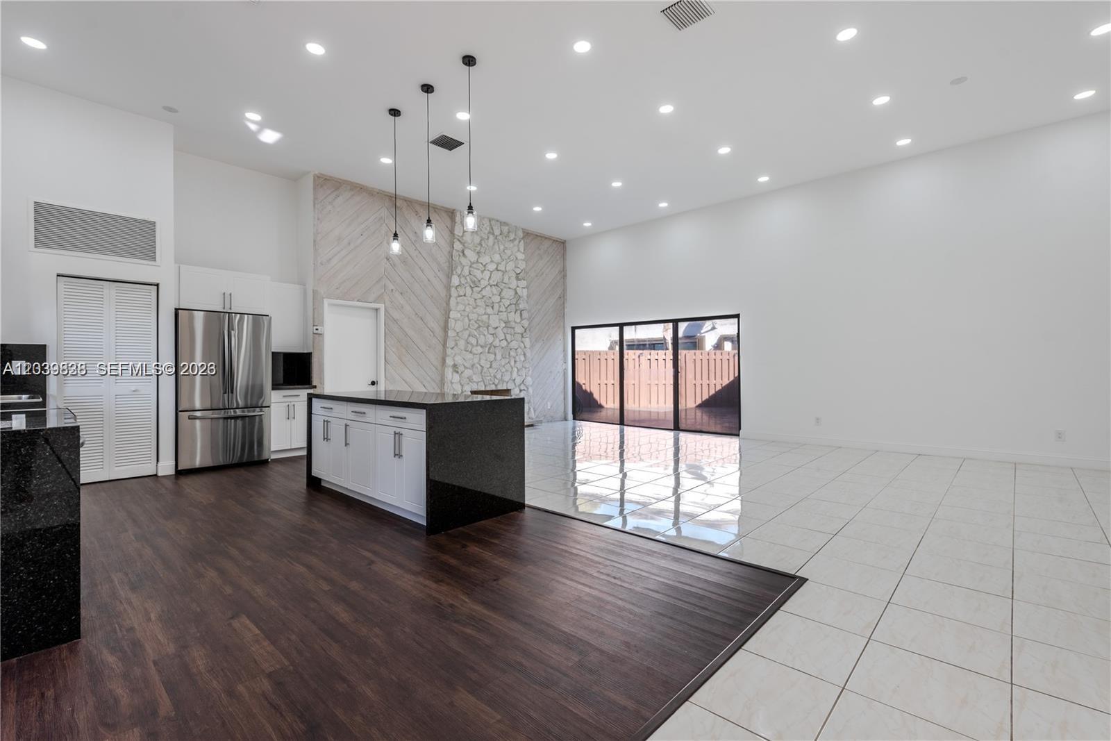 A kitchen and living area with dark wood floors, white tile, and a stone fireplace — 601 Leslie Dr, Hallandale Beach FL 33009, HALLANDALE BEACH, FL