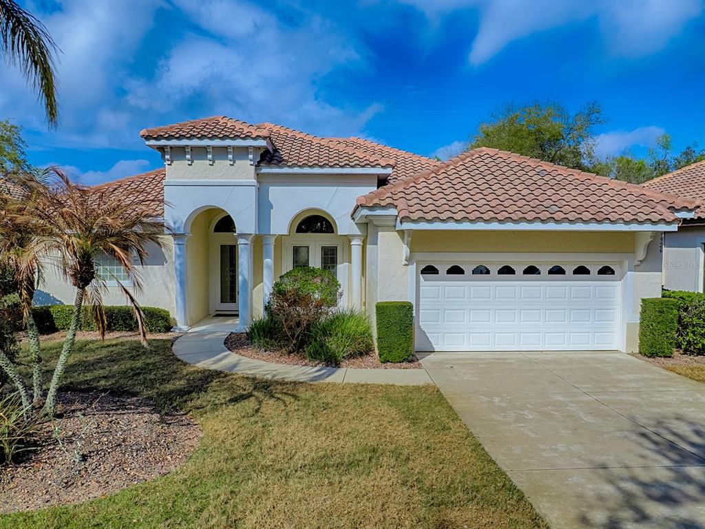 A single-story house with a tile roof, white stucco exterior, and a two-car garage — 9926 SANTA BARBARA COURT, HOWEY IN THE HILLS, FL