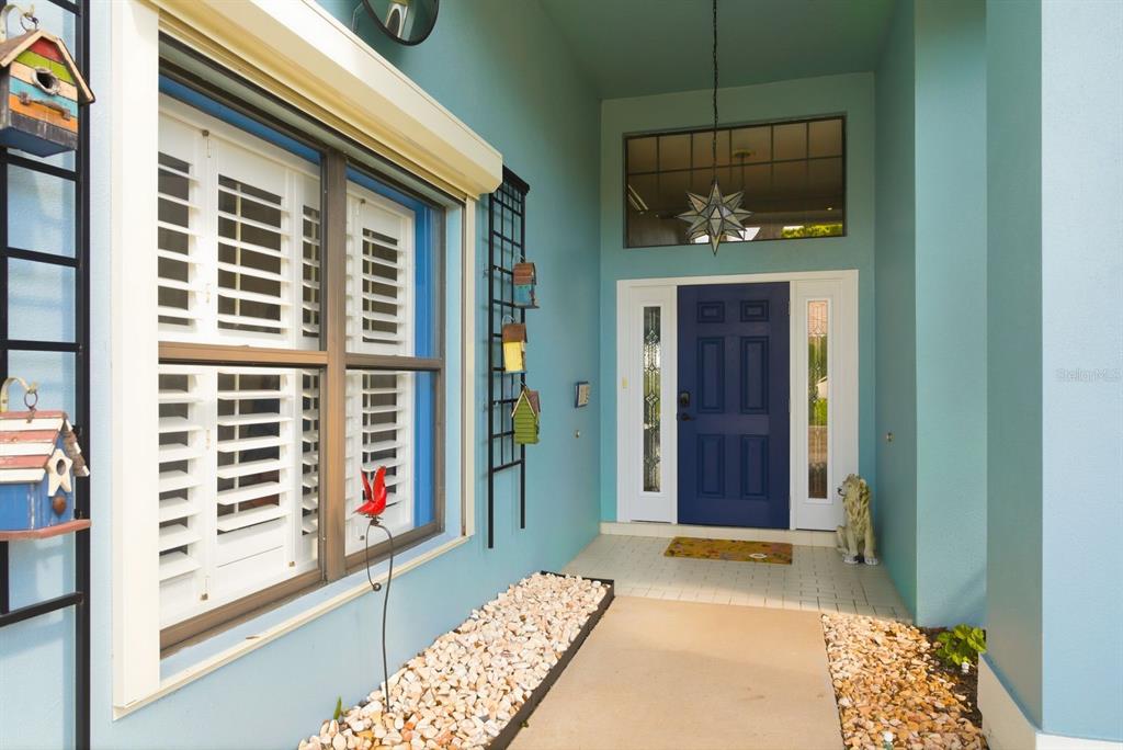 A blue house exterior features a dark blue front door, white shutters, and birdhouses — 3930 TARIAN COURT, PALM HARBOR, FL