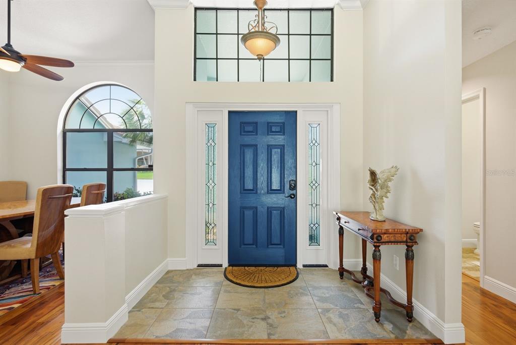 An entryway features a blue front door, tile flooring, a transom window, and a console table — 3930 TARIAN COURT, PALM HARBOR, FL