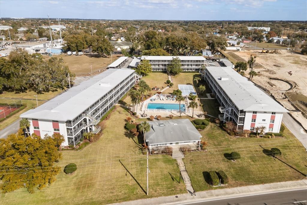An aerial view shows a multi-building apartment complex with a central swimming pool — 1700 6TH STREET NW UNIT B24, WINTER HAVEN, FL
