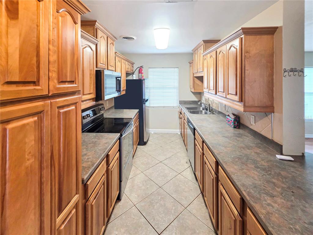 A galley kitchen features wood cabinets, laminate countertops, and tile flooring — 5117 LAKE HOWELL ROAD, WINTER PARK, FL