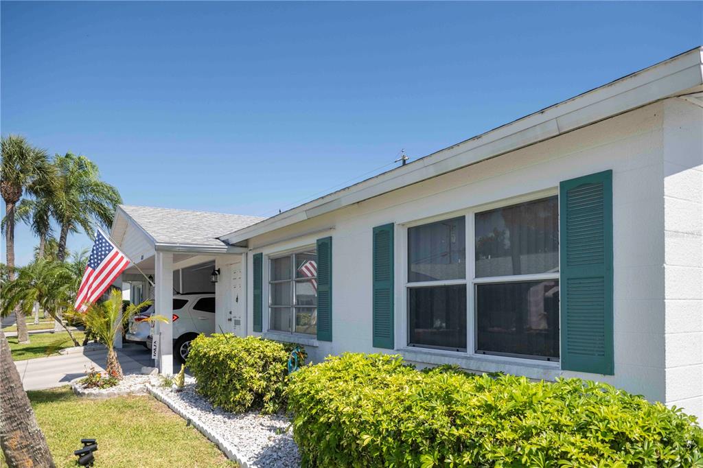 A white house exterior features green shutters, a covered carport, and a front lawn — 6024 CORAL WAY, BRADENTON, FL