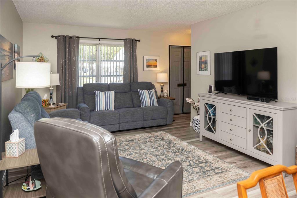 A living room features a gray sofa, a leather recliner, and a television on a console — 6024 CORAL WAY, BRADENTON, FL
