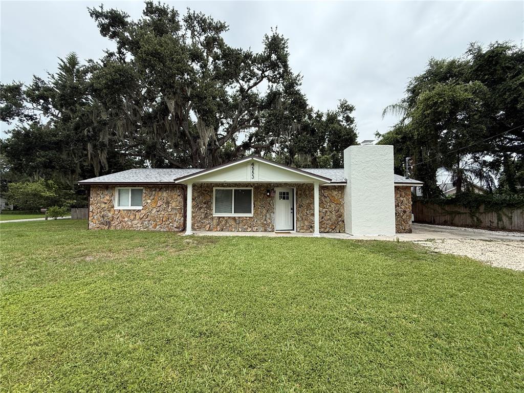 A single-story house with a stone facade, a white chimney, and a large oak tree — 4553 EDITH STREET, NEW PORT RICHEY, FL