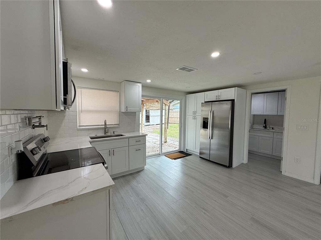 A modern kitchen features white cabinets, stainless steel appliances, and light wood-look flooring — 4553 EDITH STREET, NEW PORT RICHEY, FL
