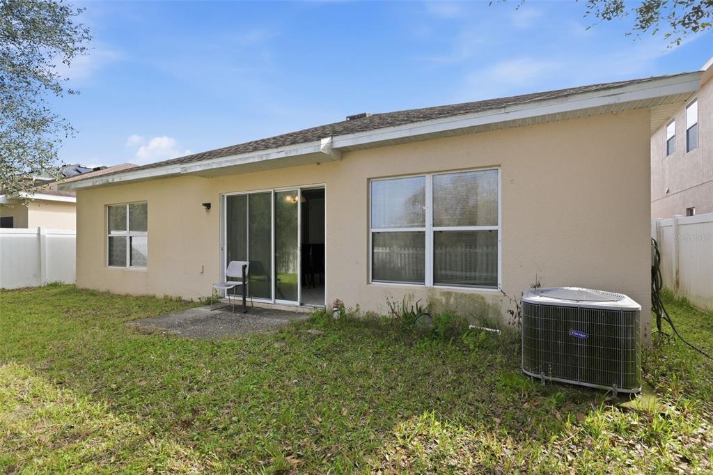 The exterior view shows the back of a beige house with a sliding glass door — 2772 BIG TIMBER DRIVE, KISSIMMEE, FL