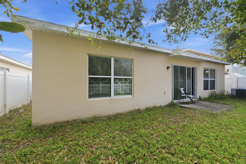 The exterior back wall of a beige house features a window, sliding glass doors, and patio — 2772 BIG TIMBER DRIVE, KISSIMMEE, FL