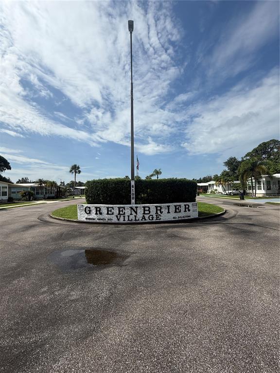 A paved road leads to a landscaped entrance sign for Greenbrier Village — 6100 62ND AVENUE N UNIT 71, PINELLAS PARK, FL