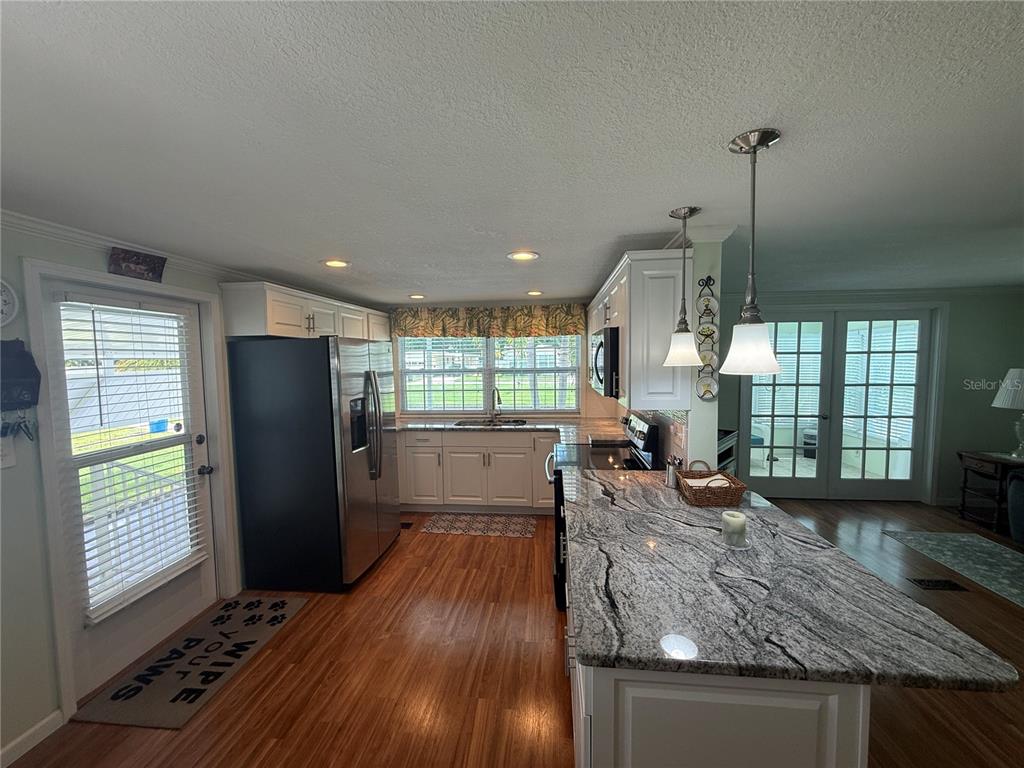 A kitchen features white cabinets, granite countertops, a large island, and stainless steel appliances — 6100 62ND AVENUE N UNIT 71, PINELLAS PARK, FL