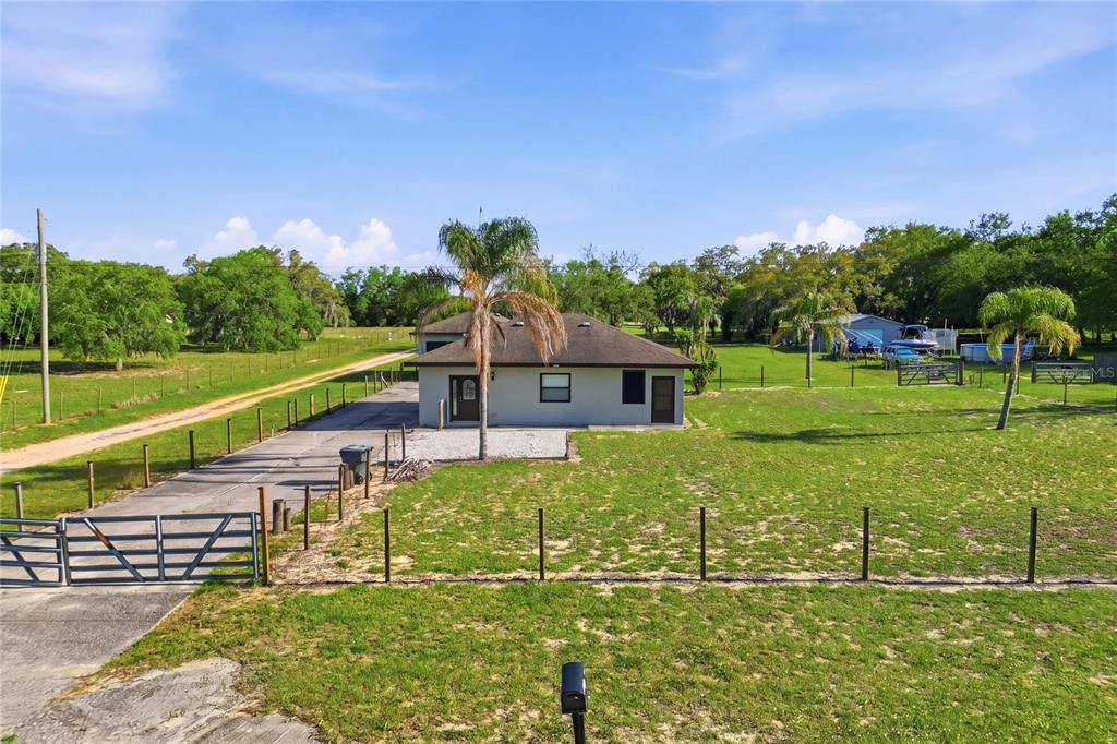 A single-story house with a palm tree sits on a large, fenced grassy lot — 29 COYER RD UNIT 2, HAINES CITY, FL