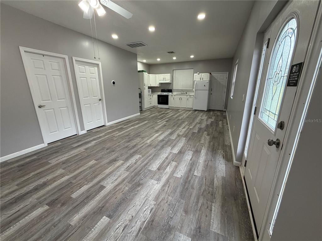 An open-concept living area features gray walls, wood-look flooring, and a white kitchen — 29 COYER RD UNIT 2, HAINES CITY, FL
