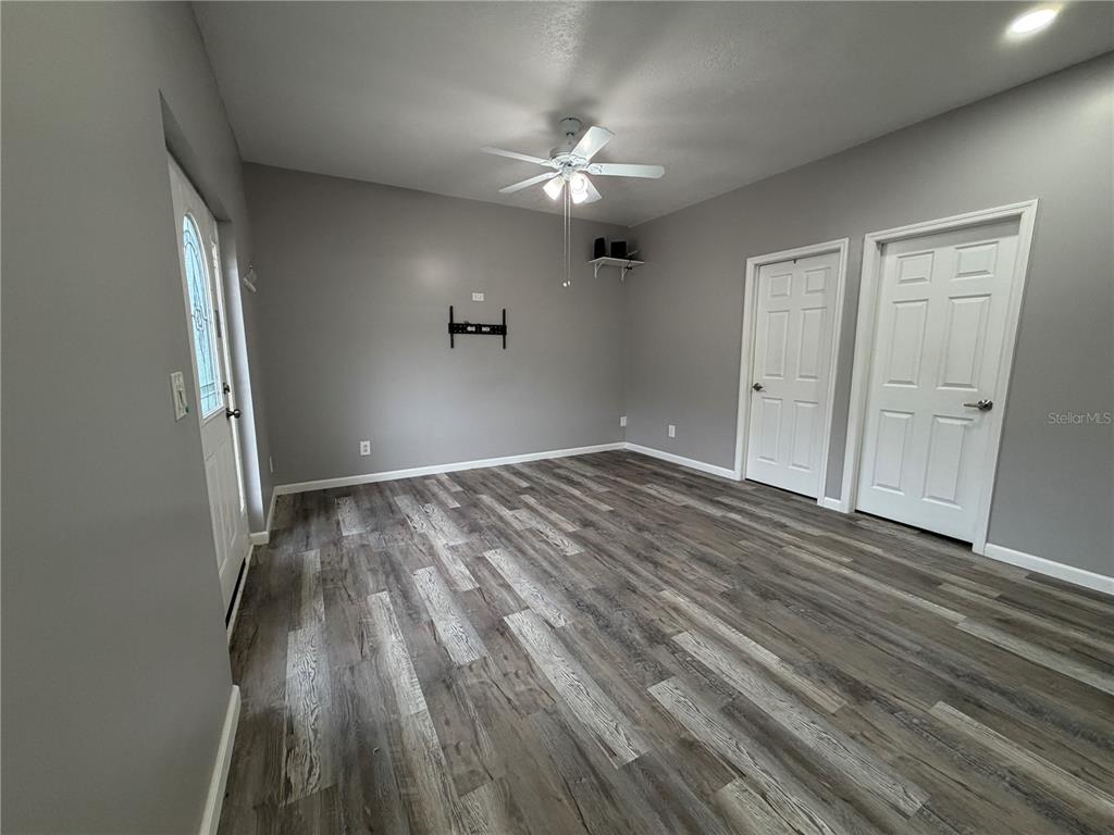 An empty room features gray walls, wood-look flooring, a ceiling fan, and two white doors — 29 COYER RD UNIT 2, HAINES CITY, FL