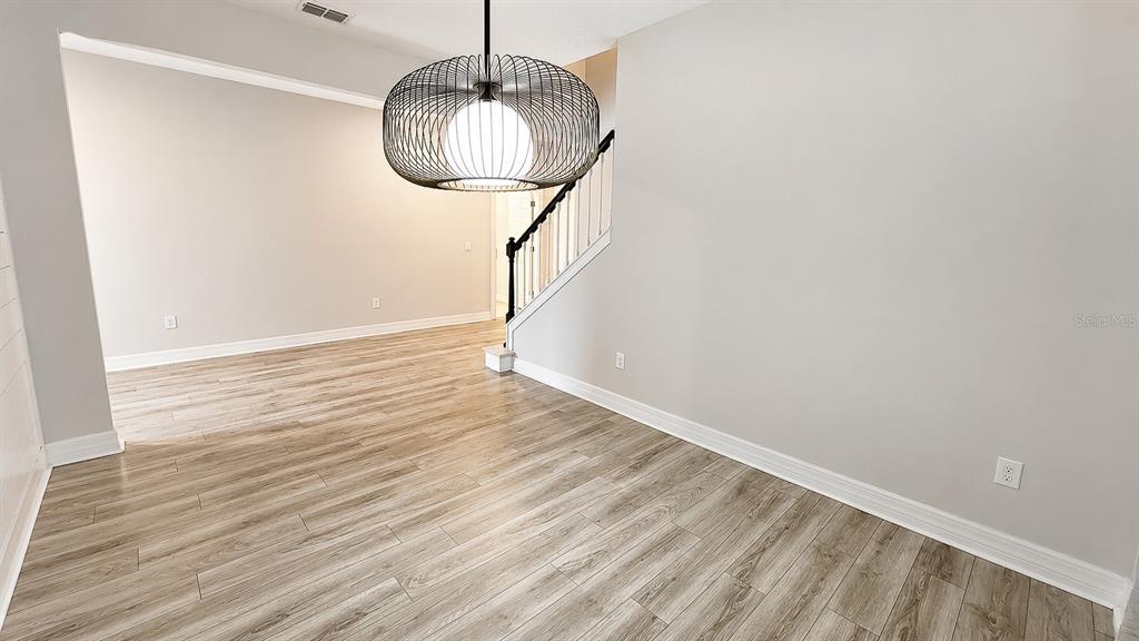 A dining area features light wood-look flooring, a modern wire pendant light, and a staircase — 10903 GREEN HARVEST DRIVE, RIVERVIEW, FL
