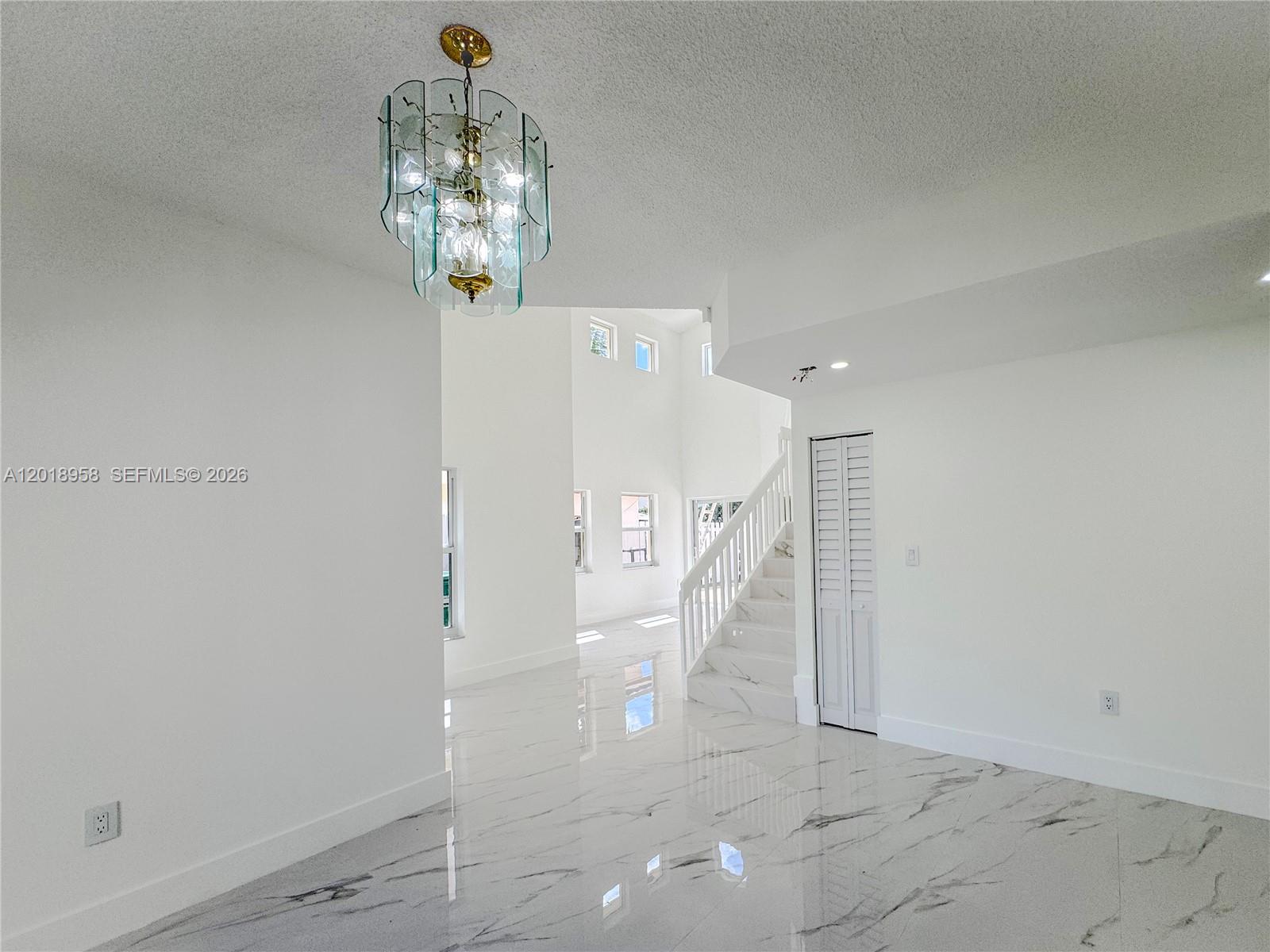 A bright, open-concept room features white walls, marble-patterned tile floors, and a glass chandelier — 15428 SW 50th Ter # 0, Miami FL 33185, MIAMI, FL