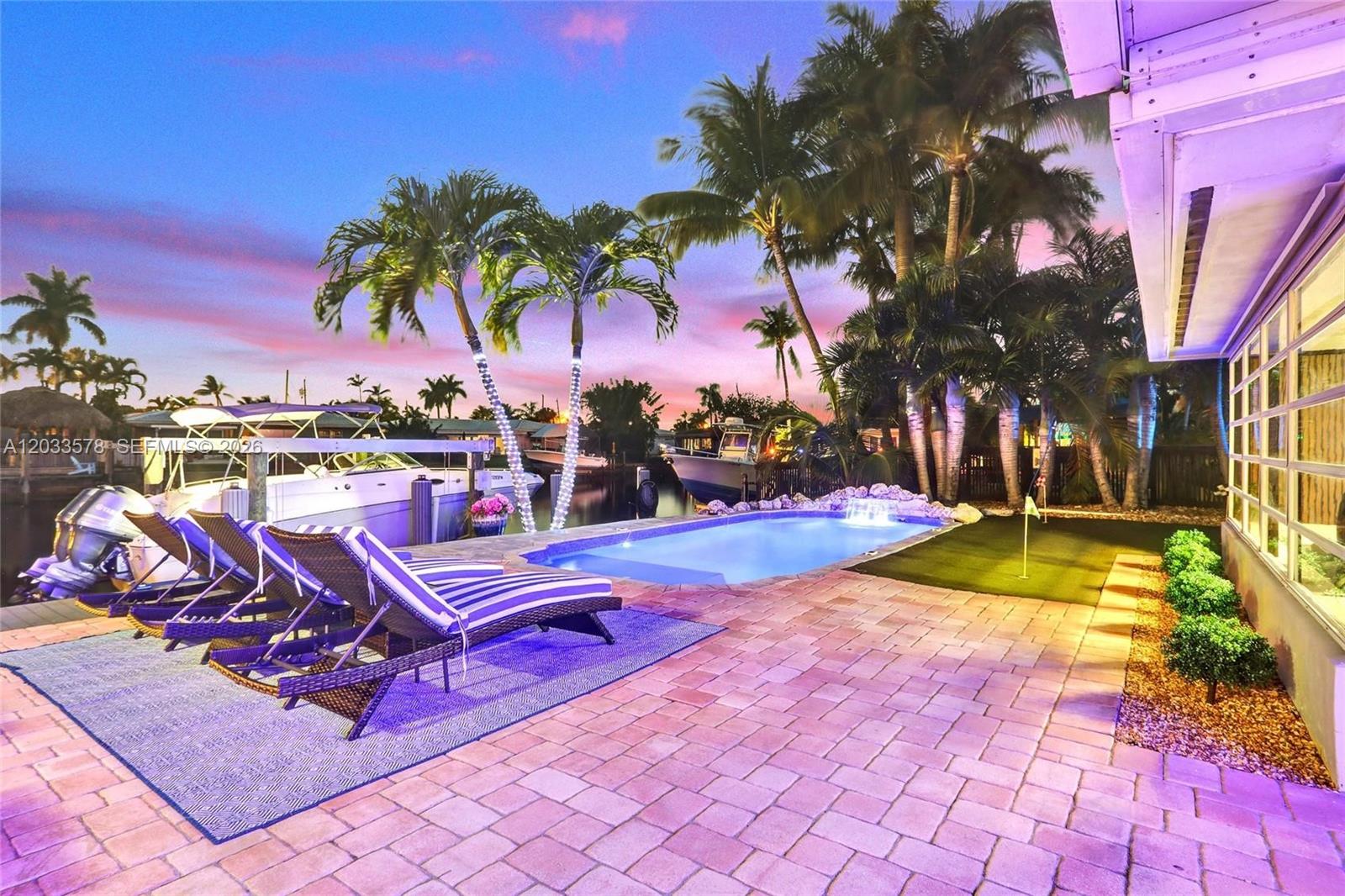 A patio features a swimming pool, lounge chairs, and a putting green overlooking a canal — 200 SE 3rd St, Pompano Beach FL 33060, POMPANO BEACH, FL