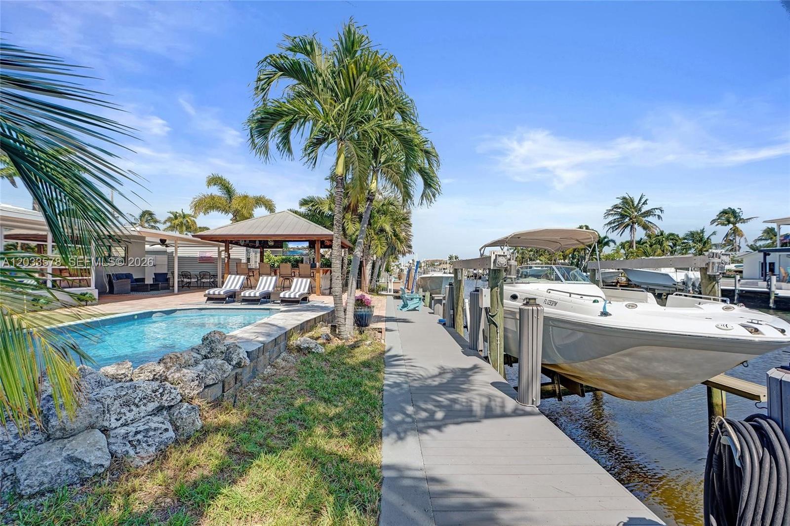 A swimming pool and tiki bar sit beside a boat dock with a moored vessel — 200 SE 3rd St, Pompano Beach FL 33060, POMPANO BEACH, FL