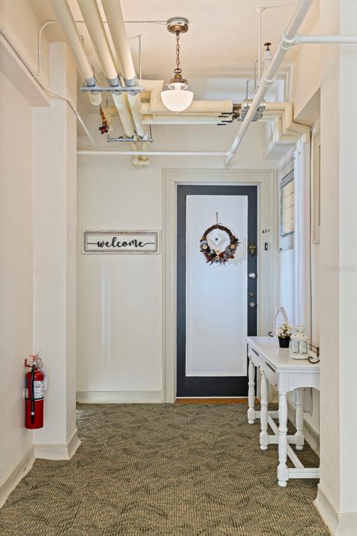 An entryway features a white door with a wreath, a console table, and exposed pipes — 130 4TH AVENUE N UNIT 602, ST PETERSBURG, FL