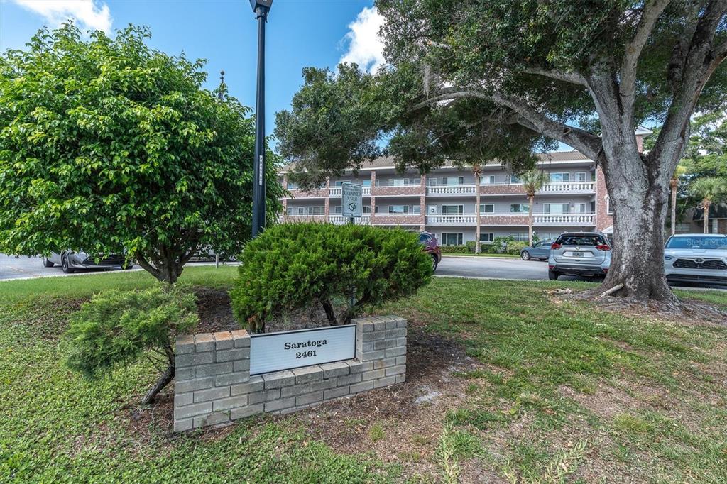 A brick sign for Saratoga 2461 sits in front of a multi-story apartment building — 2461 RHODESIAN DRIVE UNIT 45, CLEARWATER, FL