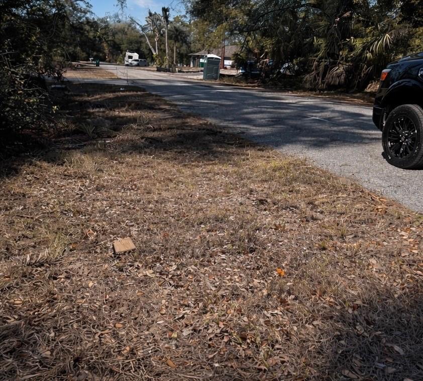 A view of a paved street with a parked vehicle and a portable toilet nearby — 17445 STANLEY AVENUE, PORT CHARLOTTE, FL