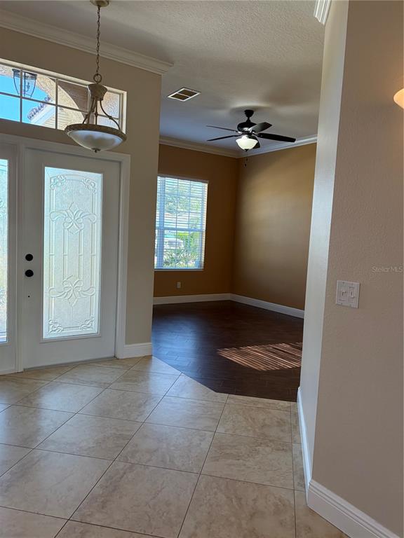 An entryway with tiled floors leads to a room with dark wood-look flooring and a ceiling fan — 7779 AROLLA PINE BOULEVARD, SARASOTA, FL