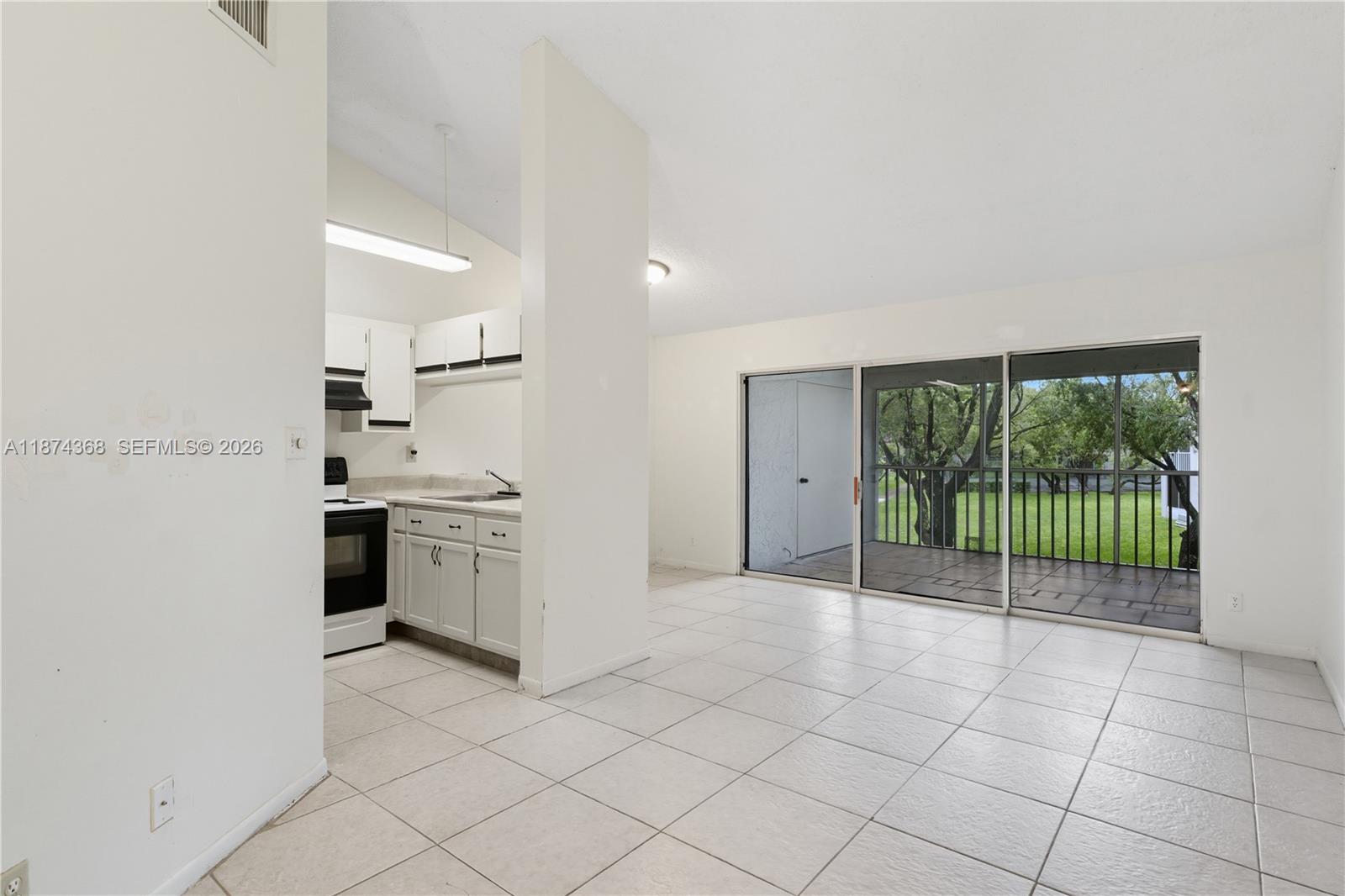 A kitchen with white cabinets opens into a living area with tile floors and sliding doors — 9167 SW 138th Pl # 9167, Miami FL 33186, MIAMI, FL