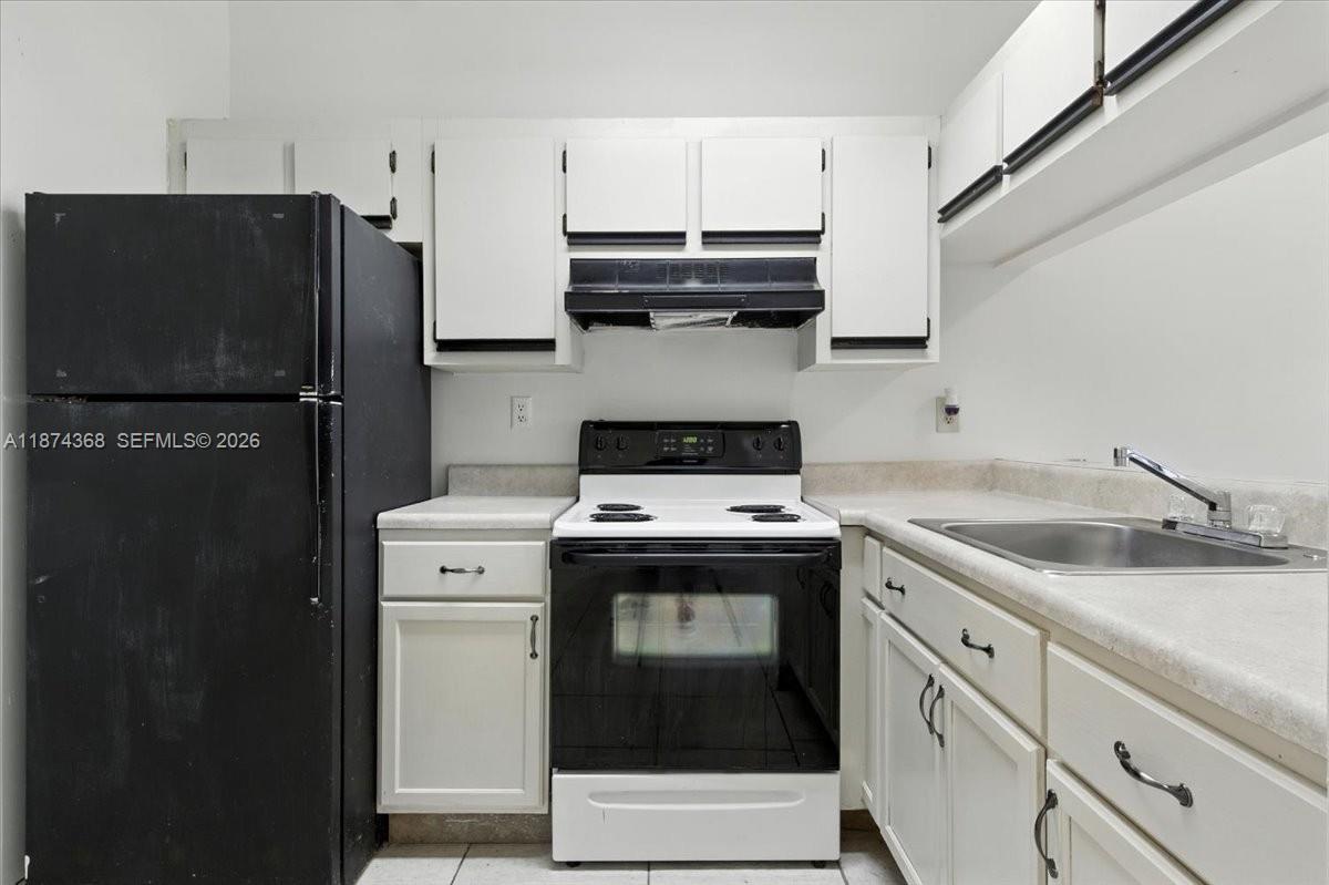 A kitchen features white cabinets, a black refrigerator, a white stove, and a stainless sink — 9167 SW 138th Pl # 9167, Miami FL 33186, MIAMI, FL
