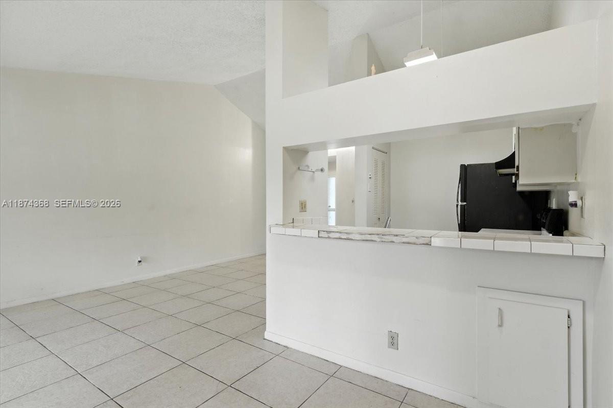 This interior view shows a tiled living area with a kitchen pass-through counter — 9167 SW 138th Pl # 9167, Miami FL 33186, MIAMI, FL