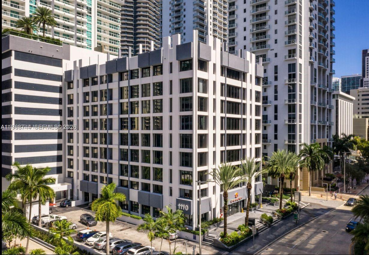 An exterior view of a multi-story office building with a white grid facade and parking — 1110 Brickell Ave # 804, Miami FL 33131, MIAMI, FL