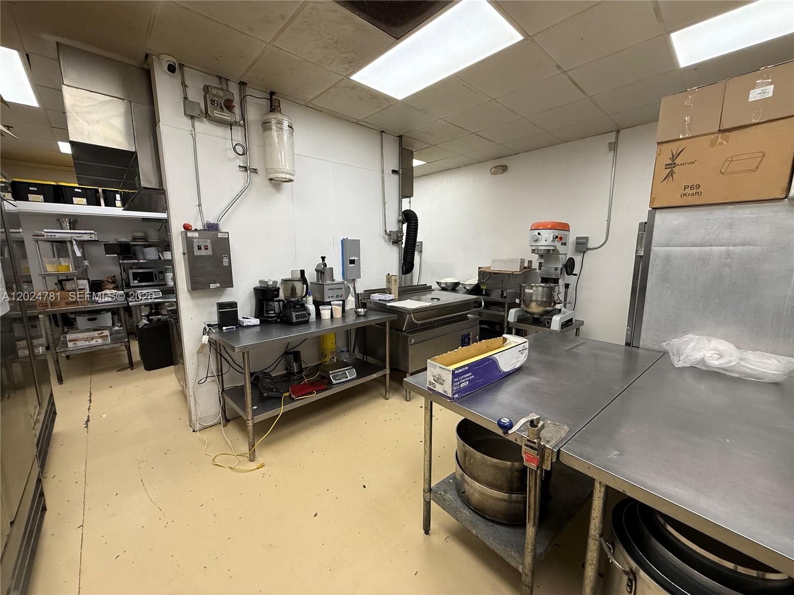 A commercial kitchen features stainless steel prep tables, industrial mixers, and various food processing equipment — PEMBROKE PINES, FL