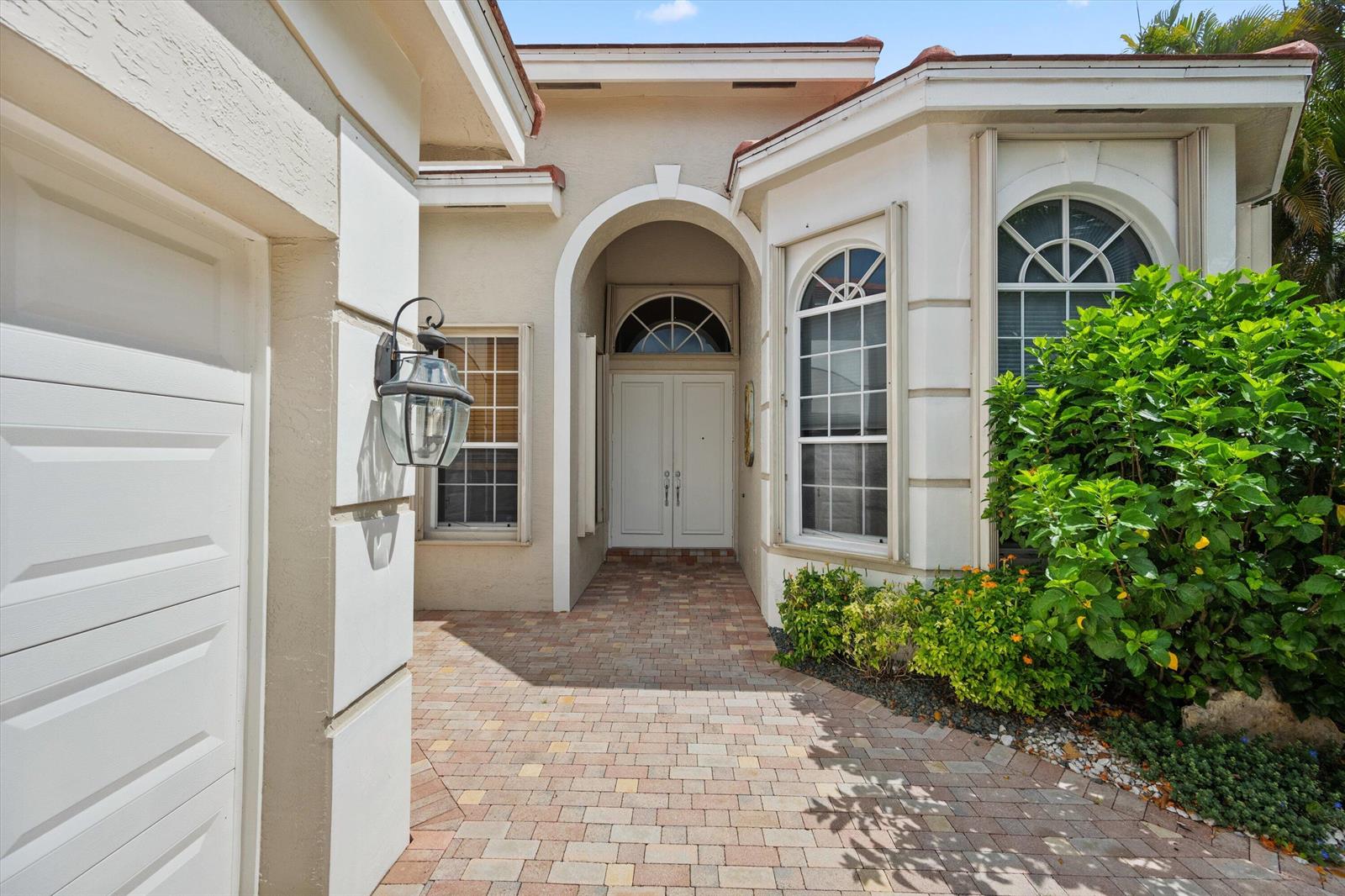 A paved walkway leads to the double front doors of a stucco house with arched windows — 10911 Royal Devon Way, Lake Worth FL 33449, LAKE WORTH, FL