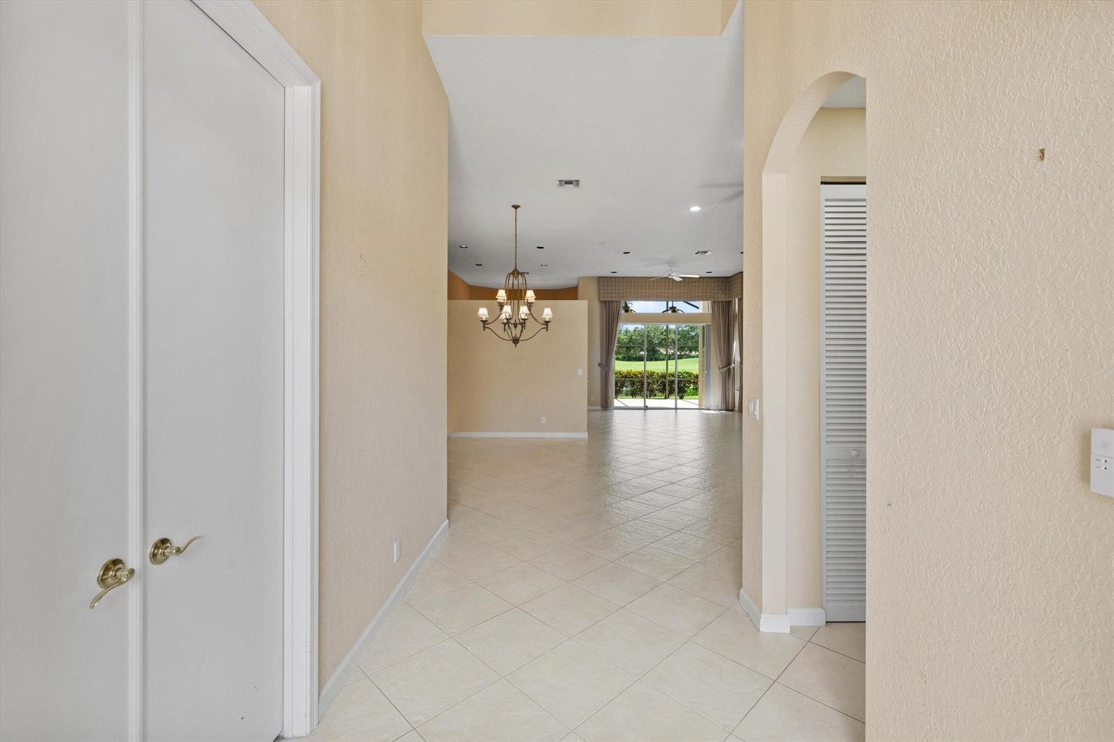 A view from a hallway looking into a living area with tile floors and chandelier — 10911 Royal Devon Way, Lake Worth FL 33449, LAKE WORTH, FL