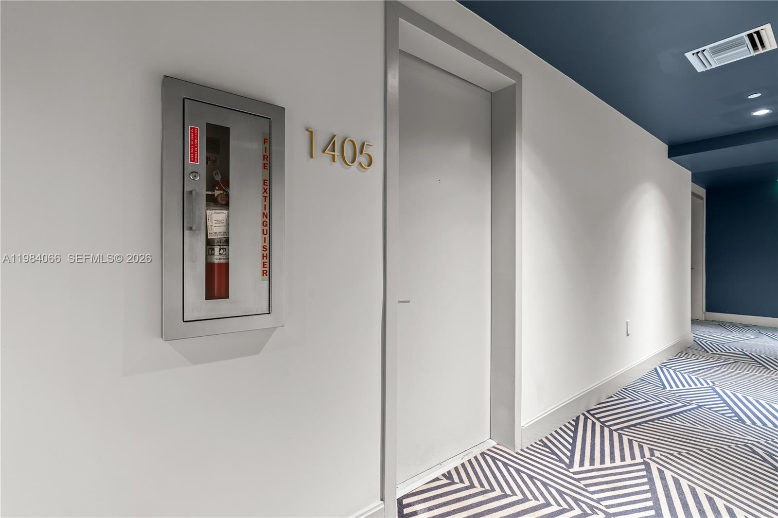 A hallway features a door labeled 1405, a recessed fire extinguisher cabinet, and patterned carpeting — 45 SW 9th St # 1405, Miami FL 33130, MIAMI, FL