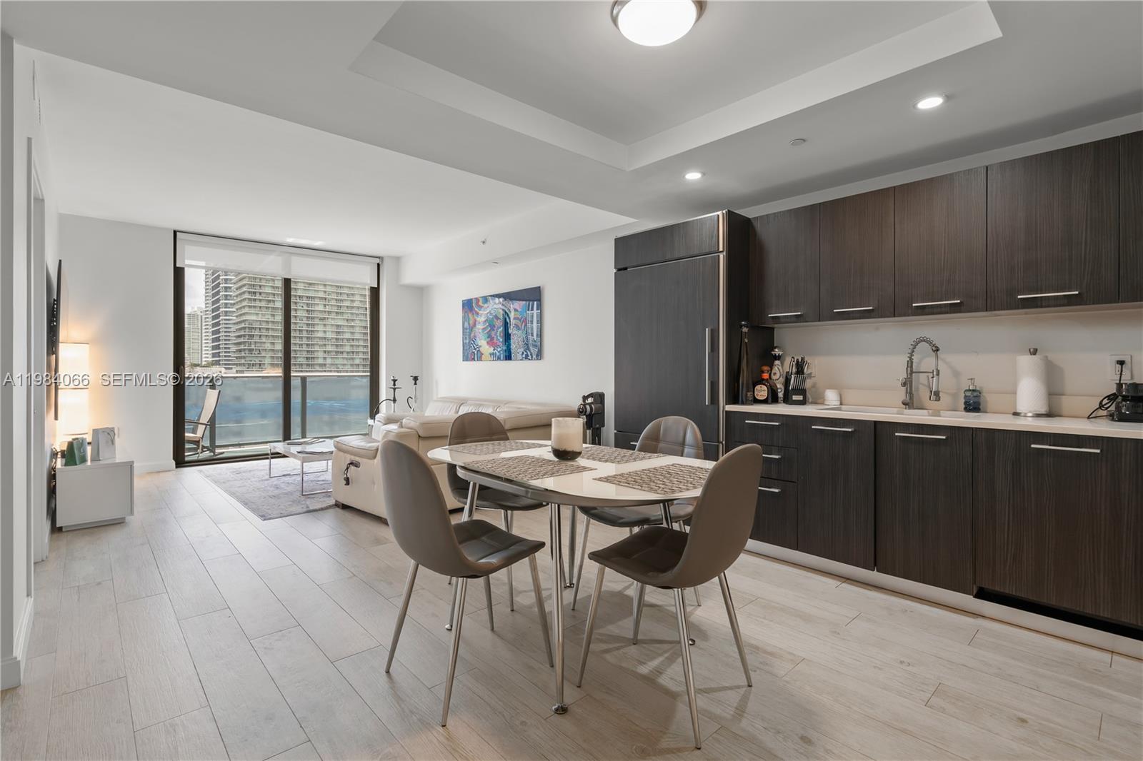 A modern open-concept living and dining area features dark wood cabinetry and light wood flooring — 45 SW 9th St # 1405, Miami FL 33130, MIAMI, FL