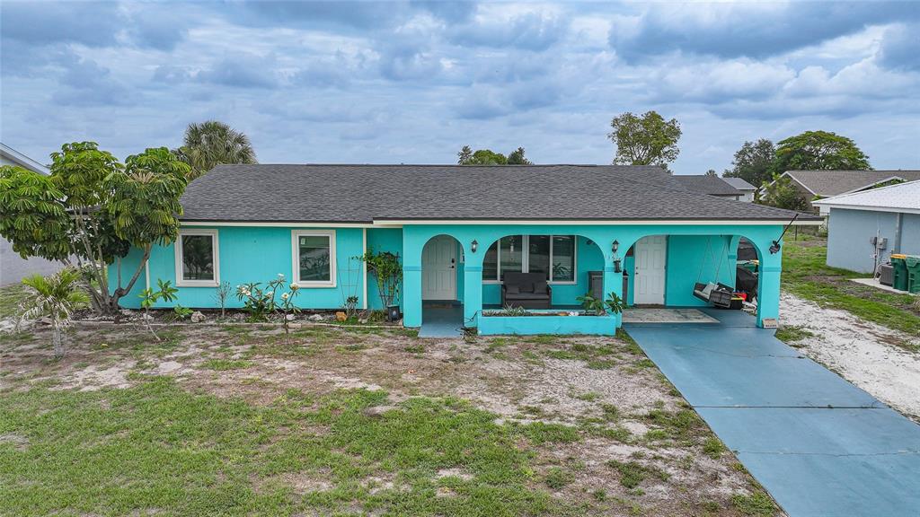 A single-story house with turquoise siding, a dark shingled roof, and an attached carport — 13518 ALBERTA AVENUE, PORT CHARLOTTE, FL