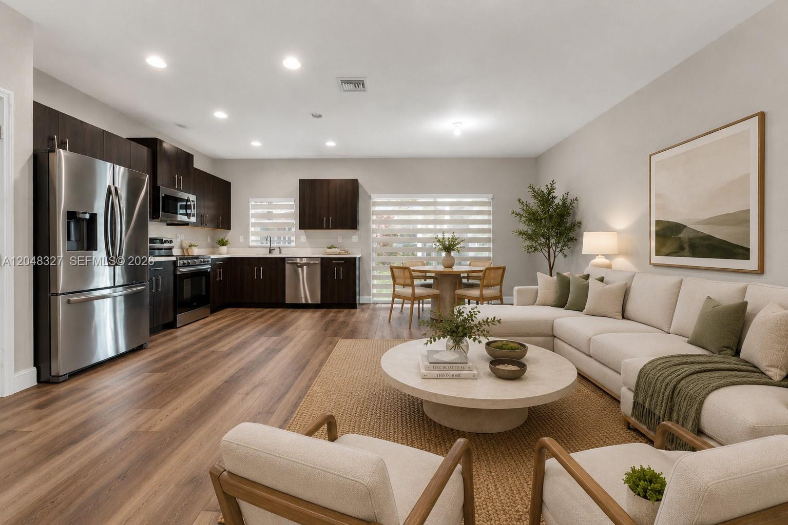 An open-concept living area features a modern kitchen with dark cabinets and a beige sectional — 4040 NW 11th St, Lauderhill FL 33313, LAUDERHILL, FL
