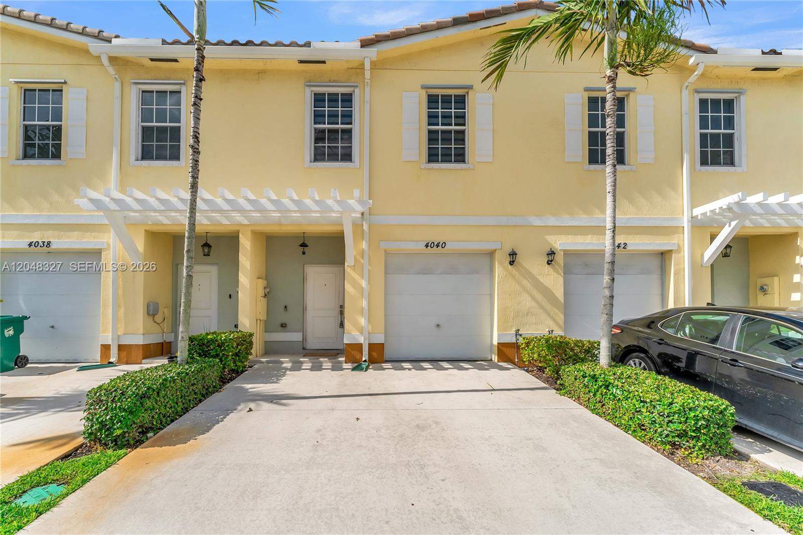 The exterior of a yellow two-story townhouse features a garage, a front door, and landscaping — 4040 NW 11th St, Lauderhill FL 33313, LAUDERHILL, FL