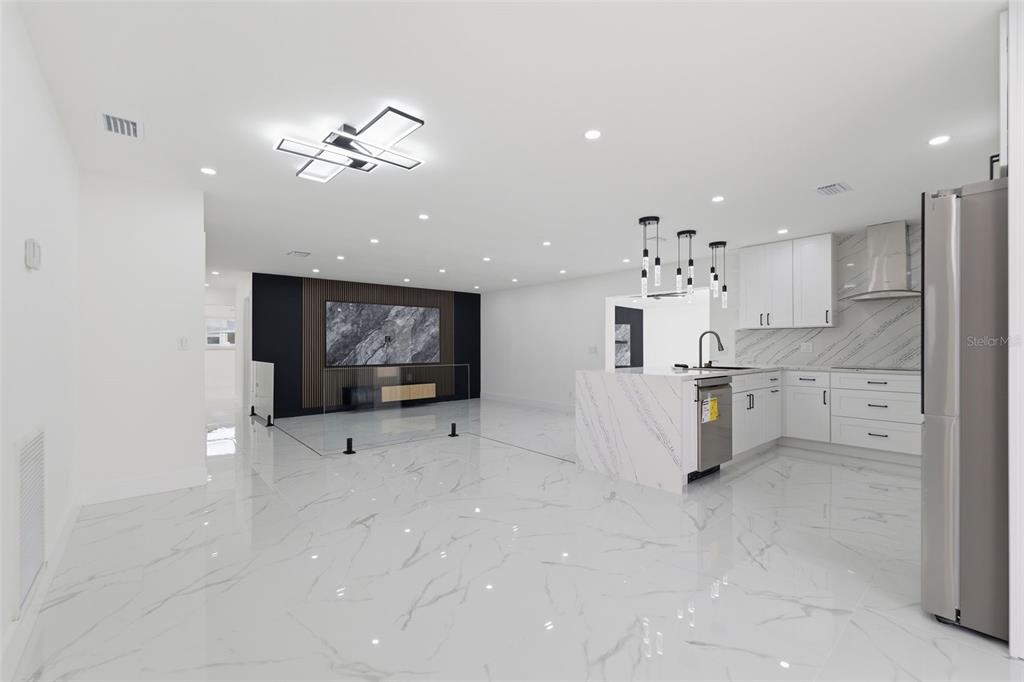 A modern open-concept kitchen and living area with white marble flooring and white cabinetry — 22368 SOUTHSHORE DRIVE, LAND O LAKES, FL