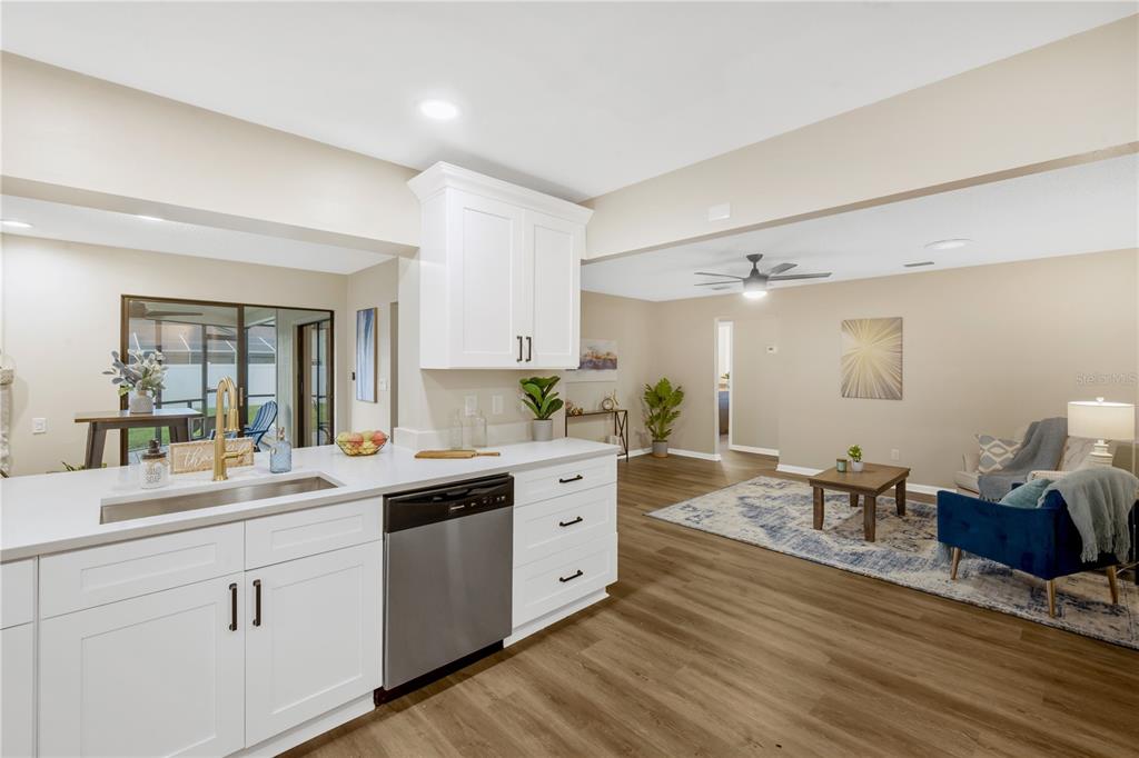 A kitchen with white cabinets and stainless steel appliances overlooks an open-concept living area — 2805 BEAGLE PLACE, SEFFNER, FL