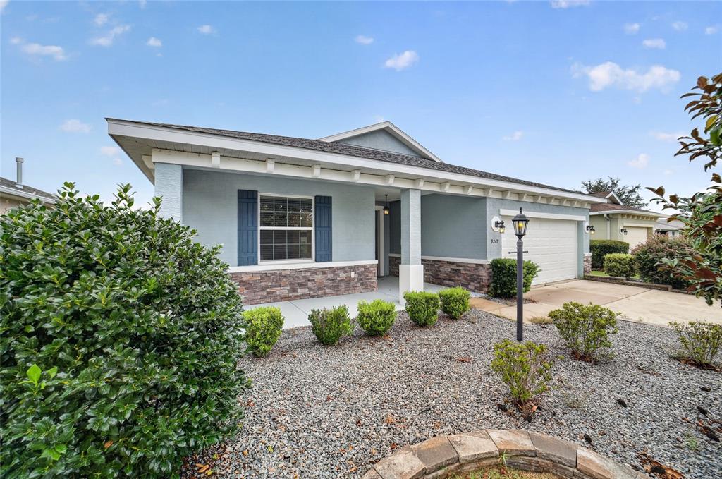 A single-story house with light blue siding, stone veneer, and a gravel front yard — 9269 SW 97TH CIRCLE, OCALA, FL
