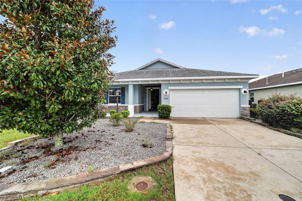 A single-story house with a blue exterior, a two-car garage, and a large magnolia tree — 9269 SW 97TH CIRCLE, OCALA, FL