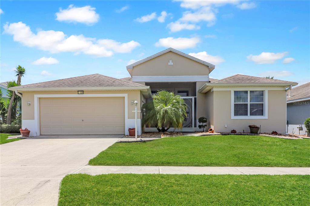 A single-story suburban house with a tan exterior, a two-car garage, and a front lawn — 27328 PINE STRAW ROAD, LEESBURG, FL